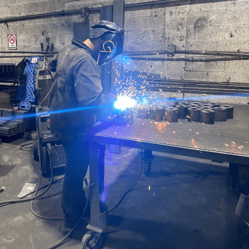 Technicians working on assembling roll-off dumpsters at a manufacturing plant.